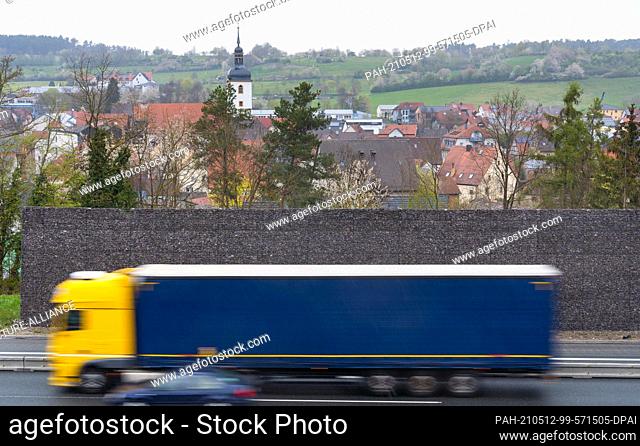 30 April 2021, Bavaria, Geiselwind: A truck drives past the gabion wall of the noise barrier near Geiselwind on the Autobahn 3