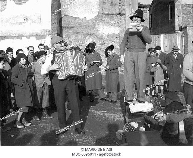 A storyteller singing with an accordion. Milan, 1950s