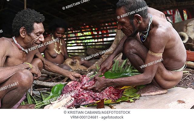 Men from the Kombai tribe preparing pork meat, Papua, Indonesia, Southeast Asia