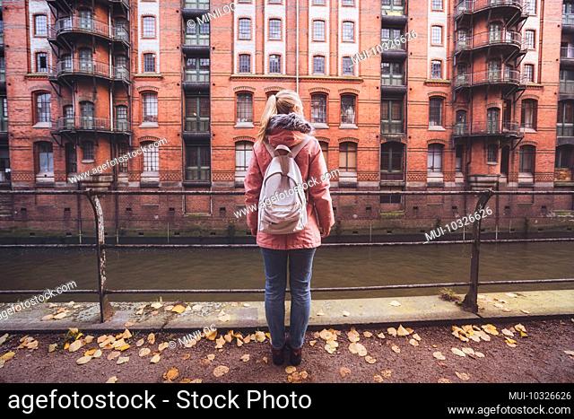Back view of a woman with a backpack looking at the historic warehouse district in Hamburg, Germany, Europe