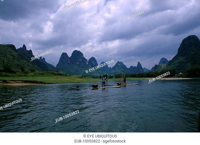 Cormorant fishermen on rafts on the River Li with limestone karst mountains in the distance