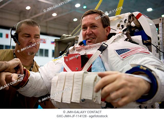 Astronaut Mike Foreman, STS-129 mission specialist, gets help in the donning of a training version of his Extravehicular Mobility Unit (EMU) spacesuit in...
