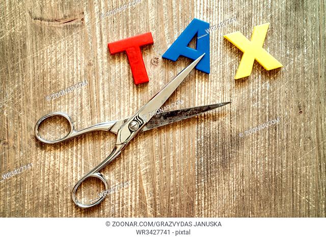 Cut of tax Concept. Scissors and the colorful plastic alphabet on wooden background