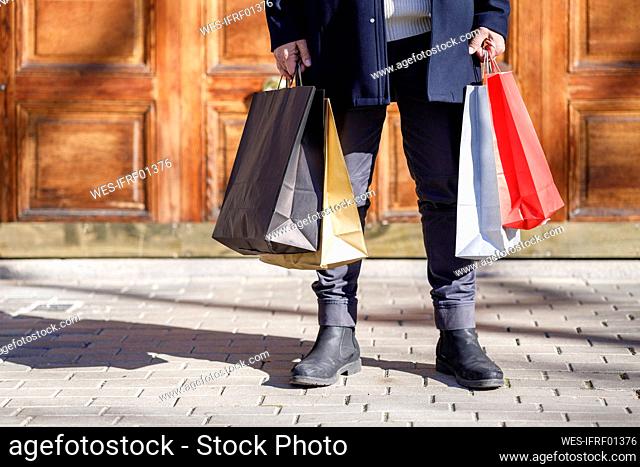 Man holding shopping bags standing on footpath