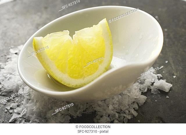 Lemon wedge with olive oil in a small bowl on salt