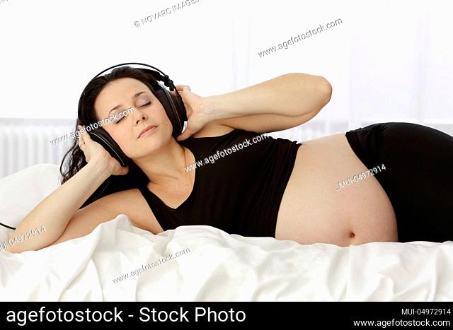 Pregnant woman listens to music with headphones