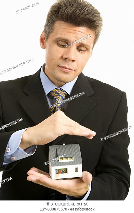 Photo of businessman holding and protecting the house