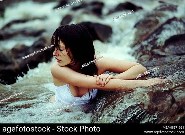 Young woman is sitting in a creek