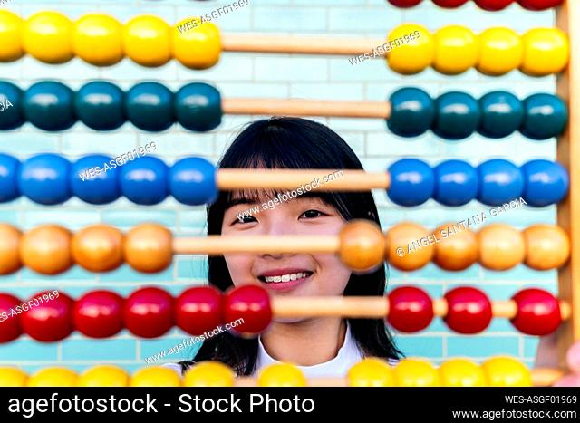 Smiling young woman looking through multi colored abacus