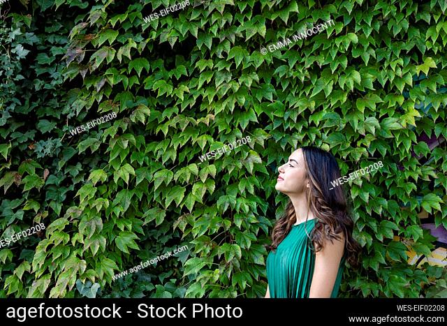 Thoughtful woman leaning on ivy leaves