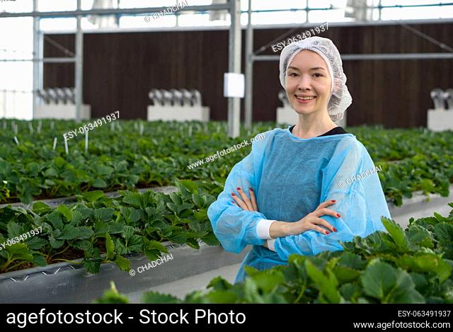 Caucasian female fruit researcher in isolation gown and disposable polyester synthetic fiber hairnet stand with arms crossed with confidence in indoor...
