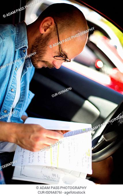 Mid adult man reading notes in car