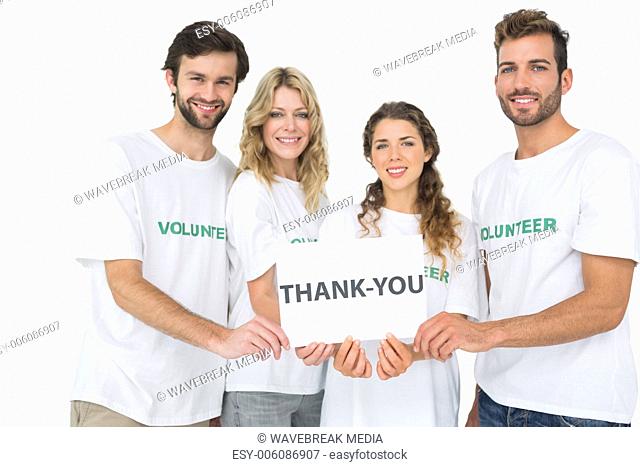 Portrait of happy volunteers holding thank you board
