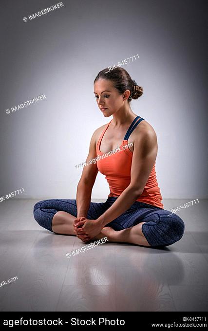 Beautiful sporty fit woman practices yoga asana Baddha konasana, bound angle pose