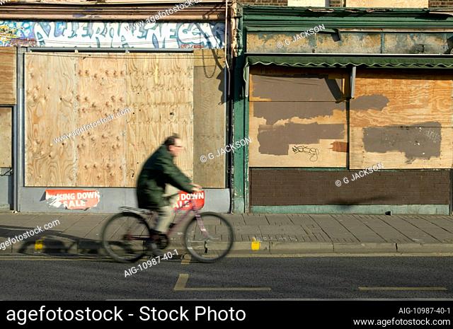 Urban Living, man cycling past boarded-up shops