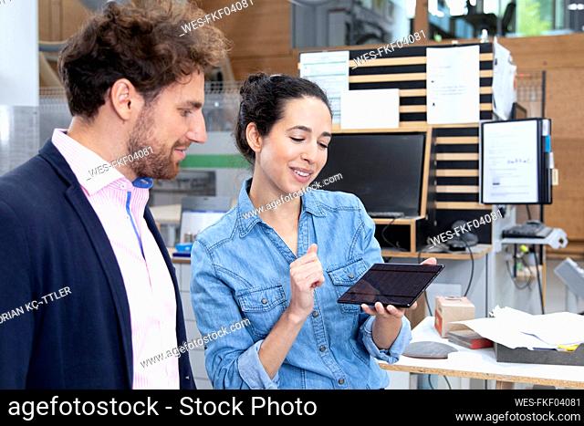 Businesswoman explaining solar energy model to male colleague in factory