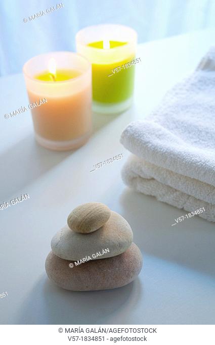 Balanced stones, towel and two lit up candles