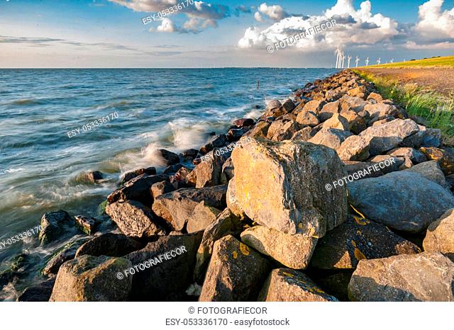 An inner lake in the Netherlands with waves striking on the stone dykes of the polder during sunset