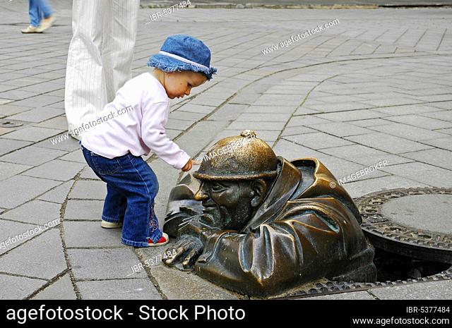 Toddler touches bronze sculpture 'Man at Work', Bratislava, Slovakia, Bratislava, bronze figure, bronze sculpture, Europe