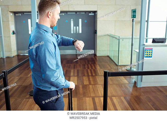 Man standing with luggage checking time