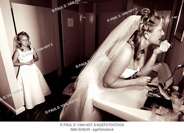 Bride preparing in bathroom with flower girl