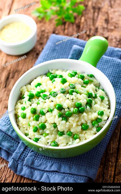 Fresh homemade creamy green pea risotto in green bowl, grated cheese in the back (Selective Focus, Focus one third into the risotto)