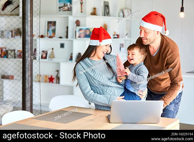 Familie mit Kleinkind mit kleinem Tannenbaum feiert Weihnachten im Videochat