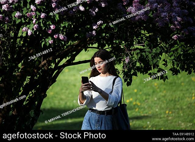 RUSSIA, MOSCOW - MAY 17, 2023: A woman is seen by a blooming lilac tree at the Kolomenskoye Museum-Reserve. Mikhail Tereshchenko/TASS