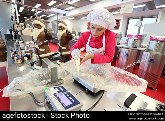 17 August 2023, Thuringia, Schmalkalden: Employee Josephiene Erbe fills nougat into a mold for Santa Clauses in Viba's production facility