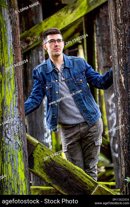 Portrait of a young man on a mossy trestle bridge; Bothell, Washington, United States of America