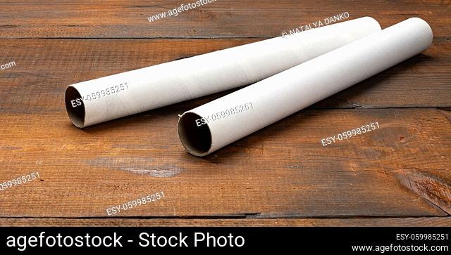 white paper tube from a roll of kitchen towels, object on a brown wooden background, top view