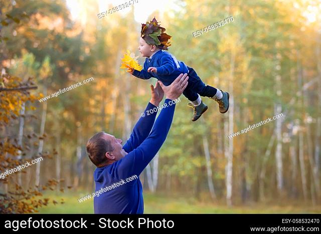Dad throws up a little son on an autumn walk.Parent with baby