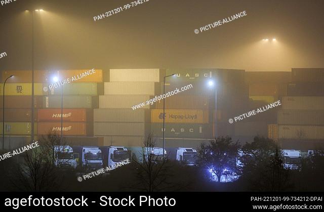 01 December 2022, Saxony, Leipzig: Trucks wait in front of a wall of sea containers at the Leipzig-Wahren transhipment station in the early morning