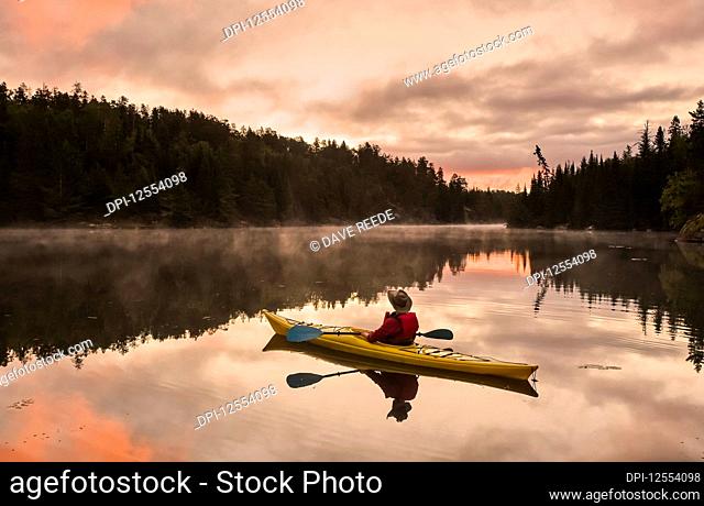 A man kayaking at sunset in the Rushing River, near Kenora; Ontario, Canada