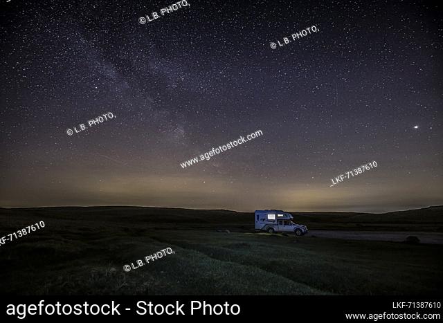 Lonely lit camper van, camper van at night under starry sky, milky way