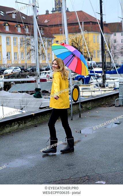 Denmark, Copenhagen, happy woman with colourful umbrella strolling at city harbour