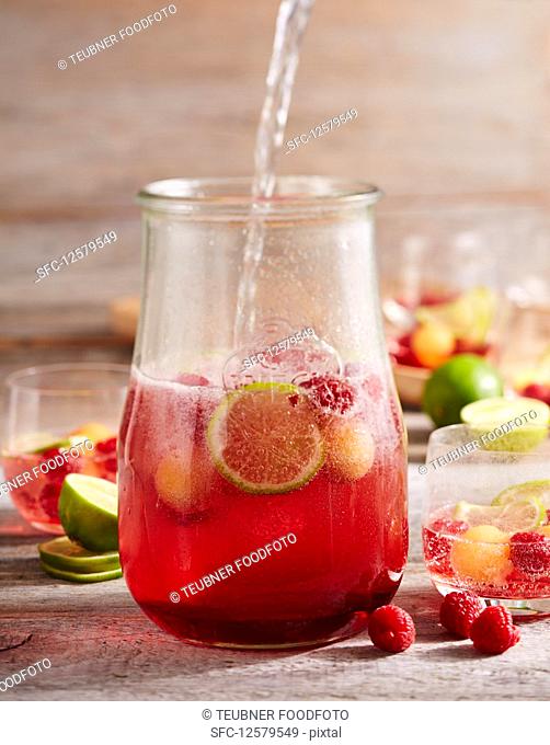 Raspberry and melon punch with champagne and limes in a jar