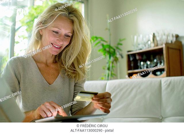 Mature woman using digital table to shop online
