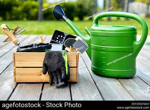 box with garden tools and watering can in summer