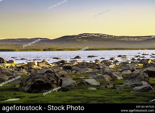 Landscape in evening light with mountains with little snow, clear sky and rocks on the shore, Swedish Lapland, Sweden