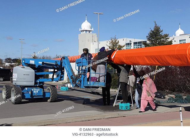 CANADA, MISSISSAUGA, Sikhs wrap cloth ribbons and decorative lights on the 135-foot freestanding hydraulic pole bearing the Sikh flag (Nishan Sahib) during the...