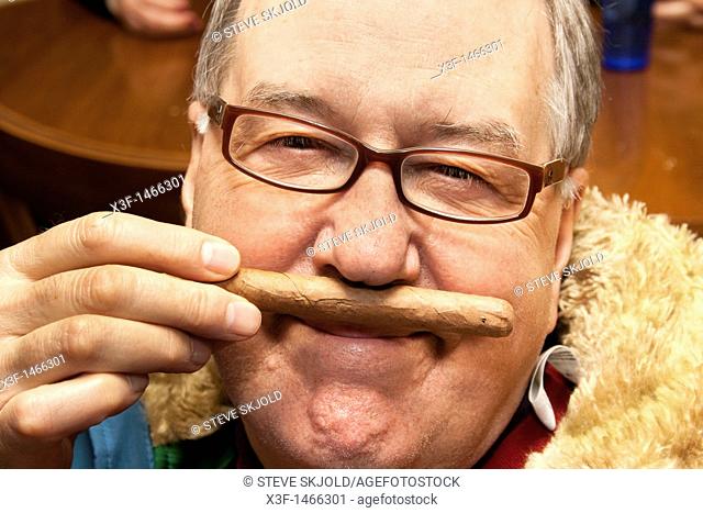 Man at his 70th birthday smelling but not smoking a Cuban cigar St Paul Minnesota MN USA