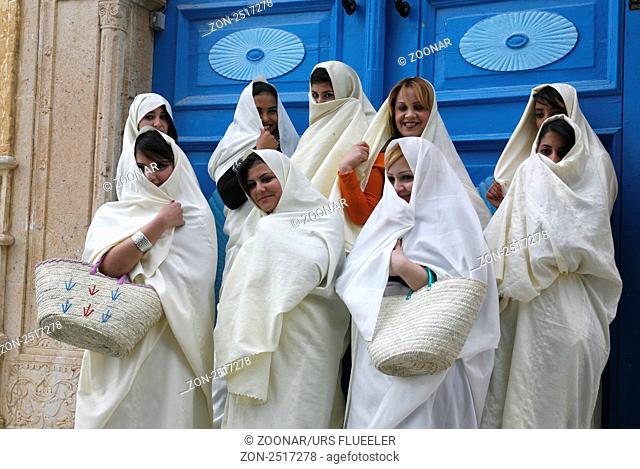 Ein Alte Fraue im traditionellen weissen Schleier in der Altstadt von Sidi Bou Said in der Daemmerung am Mittelmeer und noerdlich der Tunesischen Hauptstadt...