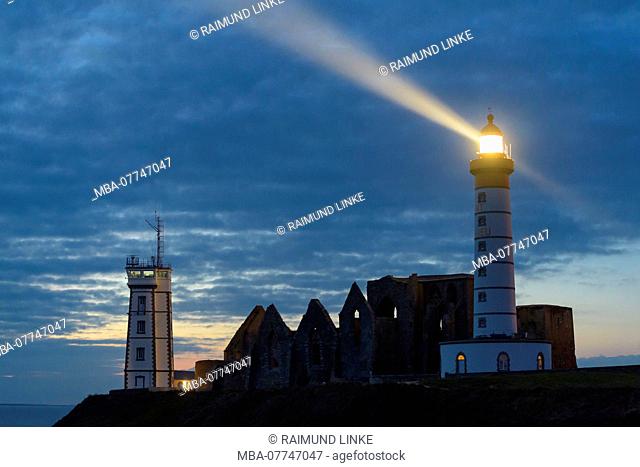 Lighthouse in the evening with beacon, Saint Mathieu lighthouse with ruin of Benedictine abbey, Pointe Saint-Mathieu, Plougonvelin, Finistere, Brittany, France