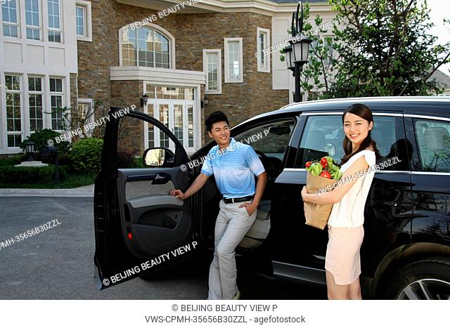 Oriental couple standing by car holding food