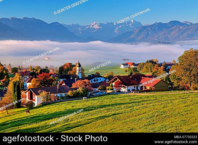 Panorama of the village with morning fog about the Riegsee in front of Wetterstein Range with Zugspitze 2962 m and Ammergauer alps, Aidling, blue country