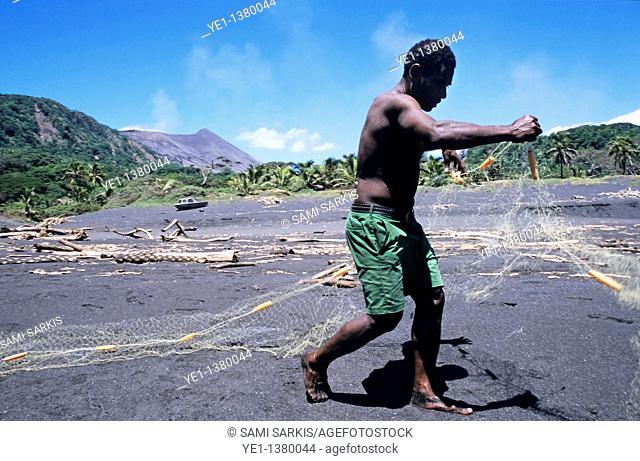 Fisherman on a black sand beach preparing his nets, Sulphur Bay Village, Tanna Island, Vanuatu