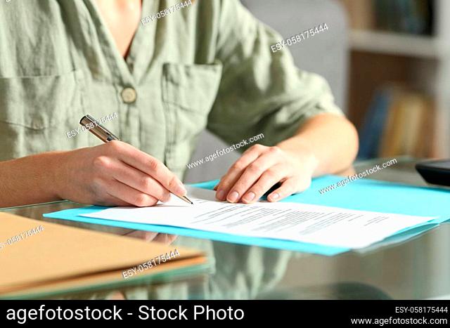 Woman hands signing contract on a glass table at home