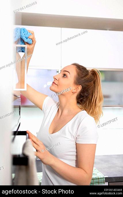 Young woman polishes a modern bright kitchen