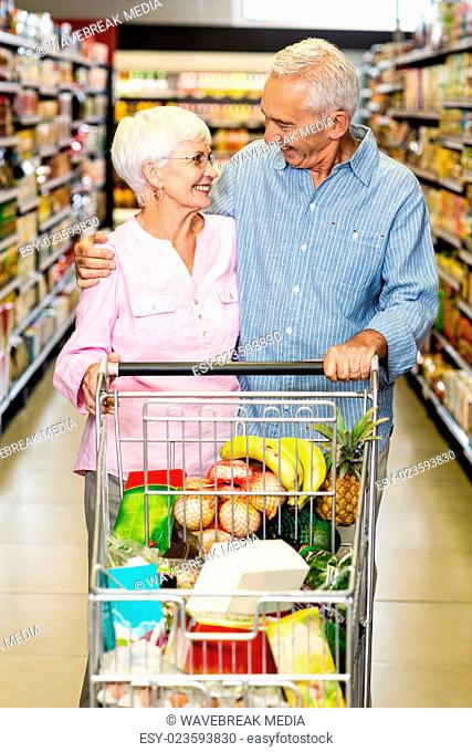 Senior couple embracing while pushing cart
